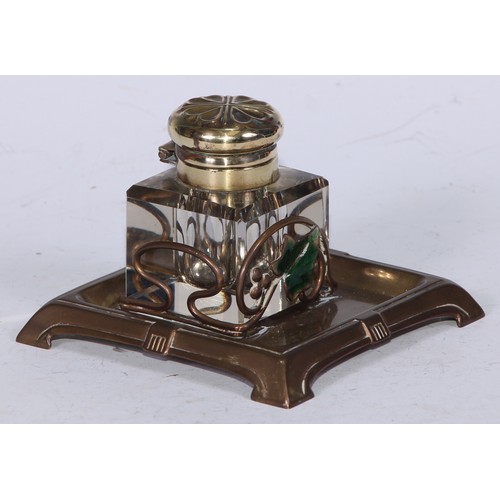 5246 - An Art Nouveau brass and enamel square inkstand, decorated with an ivy leaf, the glass well with hin... 