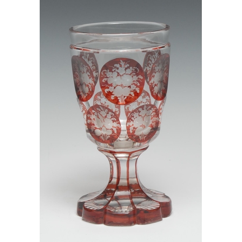 5061 - A Bohemian ruby overlaid glass spa goblet, etched with reserves of flowers and foliage, shaped circu... 