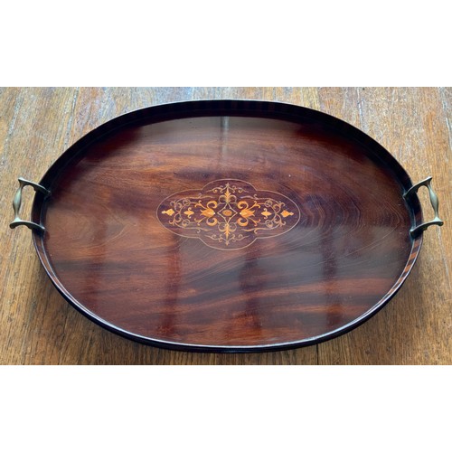 82 - An early 20th century two handled mahogany tray, the field inlaid with in coloured woods with scroll... 