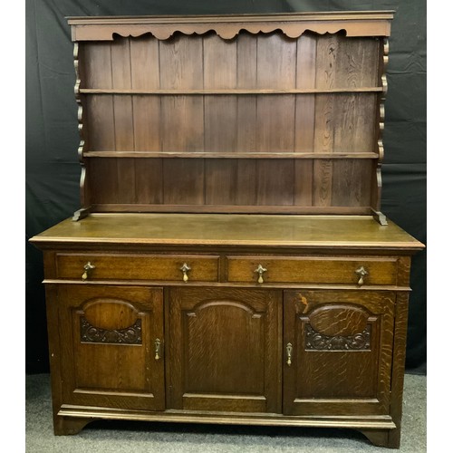 177 - An oak dresser, shaped cresting, above two open shelves, the projecting base with two drawers and tw... 