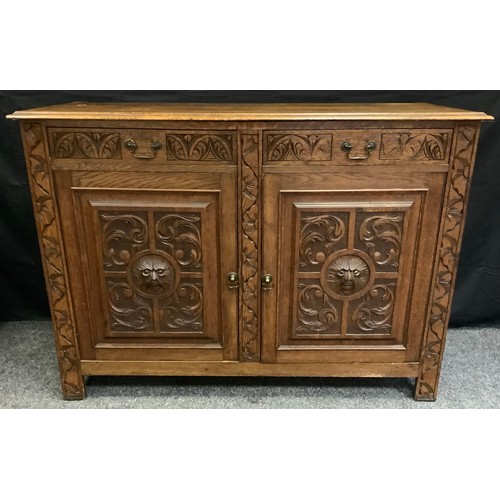 323 - An early 20th century oak sideboard, with two drawers above cupboard doors, carved  with scrolls and... 