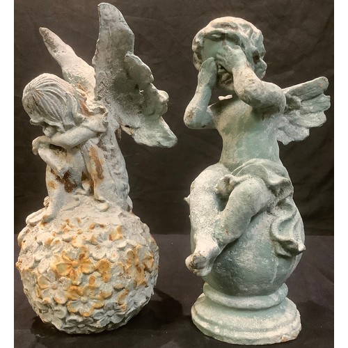 186 - A cast iron garden model of a fairy seated on a ball of flowers, 31cm high; another similar, putto o... 