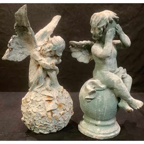 186 - A cast iron garden model of a fairy seated on a ball of flowers, 31cm high; another similar, putto o... 