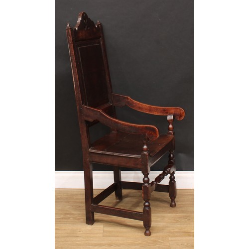 10 - An oak wainscot armchair, shaped and pierced cresting, raised and fielded panel back, shaped arms te... 