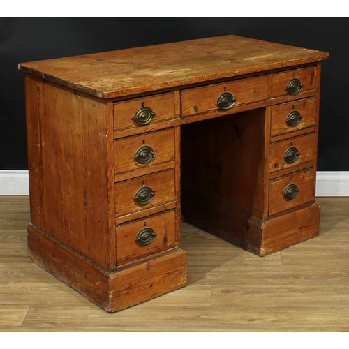 3 - A George III pine kneehole desk, oversailing top above an arrangement of drawers, oval brass handles... 