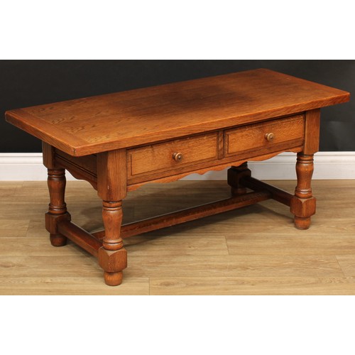 533 - An oak coffee table, rounded rectangular top above a pair of frieze drawers, turned supports, rectan... 