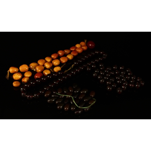 305 - A butterscotch amber necklace of twenty-six irregular formed beads, 71g; others, cherry coloured bea... 