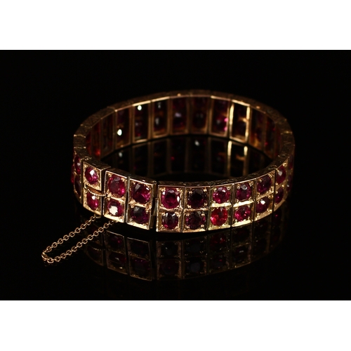 336 - An early 20th century ruby and gold coloured metal articulated panel bracelet, set in two rows of ci... 