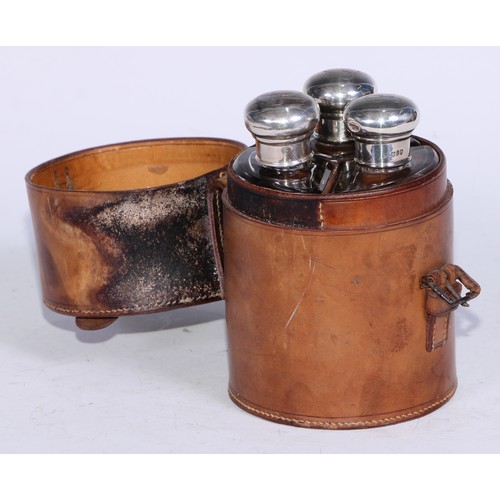 107 - A George V silver mounted travelling toilet set, comprising three triform scent or cologne flasks, s... 