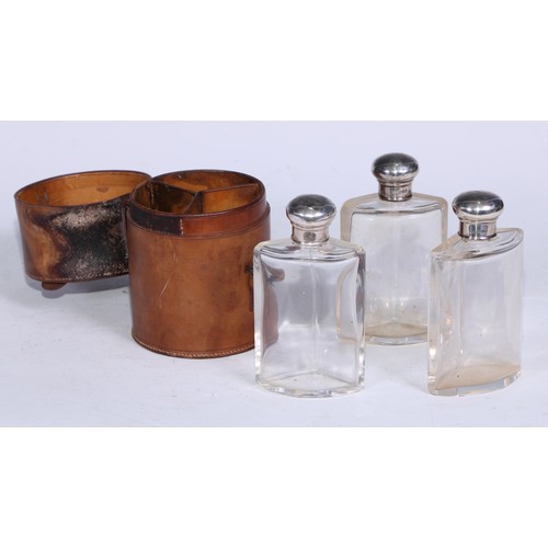 107 - A George V silver mounted travelling toilet set, comprising three triform scent or cologne flasks, s... 