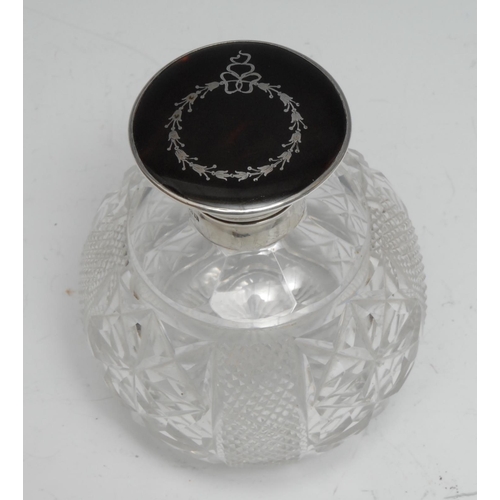 113 - A George V silver, tortoiseshell, and piqué mounted cut-glass globular scent bottle, the hinged cove... 