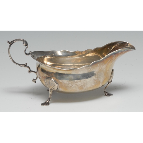 72 - A George III Provincial silver sauce boat, acanthus-capped double-scroll handle, wavy border, pad fe... 