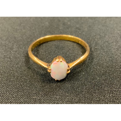 294 - An opal solitaire ring, oval opal flashing red, violet, Green colour play, 22ct gold shank, size W, ... 