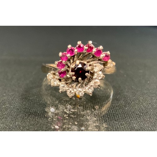 123 - A ruby and diamond cluster ring, central deep red ruby within writhen frame inset with nine diamonds... 