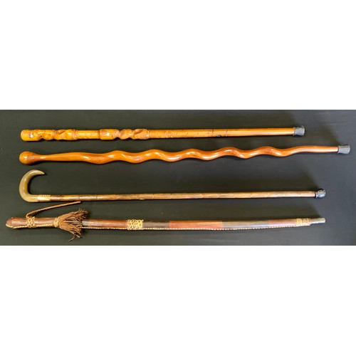 63 - A stained horn walking stick, gold plated ferule;  others carved Maori style;  North African, etc (4... 