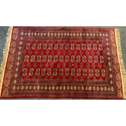 78 - A Bohkara type rug, central three rows of geometric medallions, within multi band border, deep red g... 