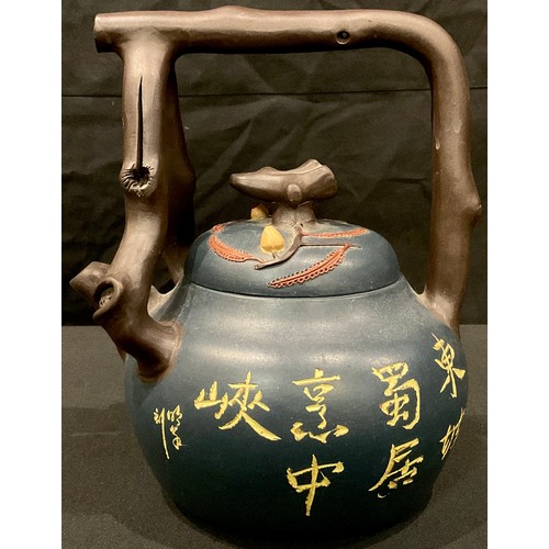 76 - A Chinese terracotta tea kettle, with naturalistic branch handle and spout, glazed in blue with scri... 