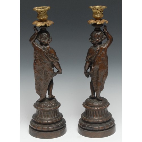 185 - A pair of sculptural 19th century French bronzed and parcel-gilt figural candlesticks, each cast as ... 