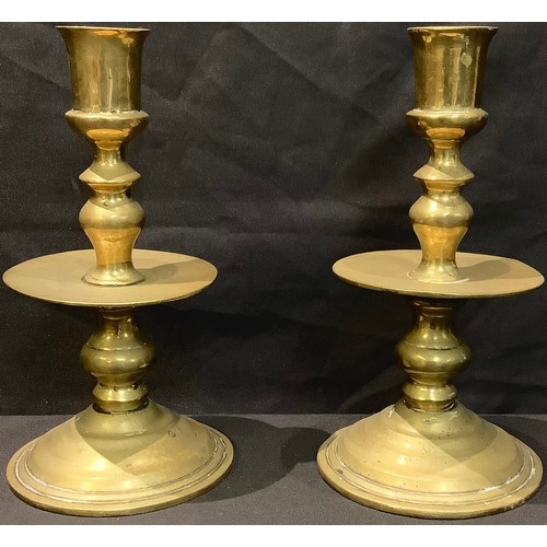 498 - A pair of Dutch brass Heemskerk candlesticks, cylindrical sconces, broad central drip pans, knopped ... 