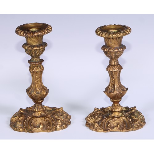 499 - A pair of Rococo ormolu candlesticks, cast with flowering C-scrolls, detachable nozzles, 17cm high, ... 