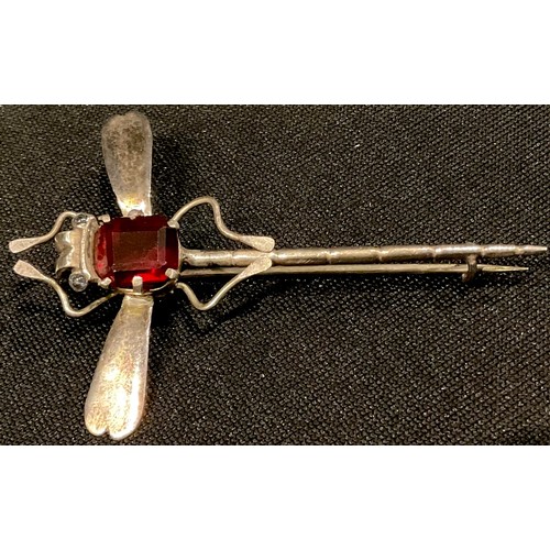 545 - A silver handmade dragonfly brooch, set with a single faceted garnet, 5.5cm long, unmarked