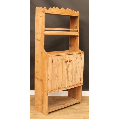 8 - A pine dresser, of narrow proportions, shaped pediment above a plate rack/shelf and a pair of doors ... 