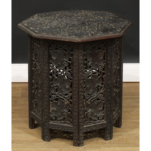 114 - A hardwood Hoshiarpur type folding table, octagonal top carved with fruiting vine, the base with pie... 