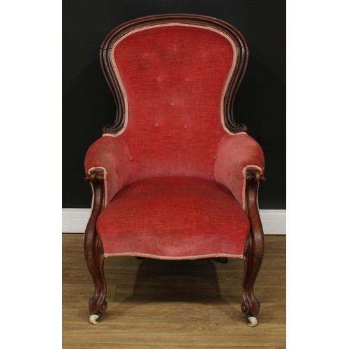 687 - A Victorian mahogany spoonback armchair, boldly carved scroll arms, cabriole legs, ceramic casters, ... 