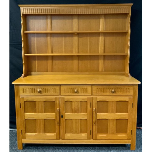 147 - An Ercol style light oak dresser, the top with two teirs of shelving, above a base with three short ... 