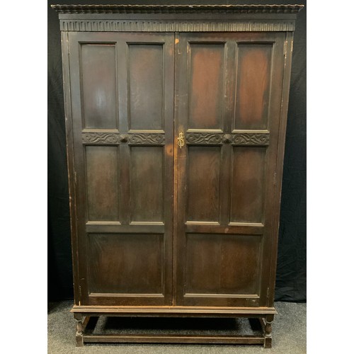 156 - A Jacobean revival oak wardrobe on stand, 197cm tall x 127cm wide x 48cm deep.