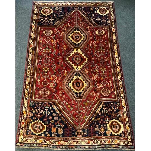 171 - A Persian Qashgai rug / carpet, triple medallion centre within a field woven with stylised flowers i... 