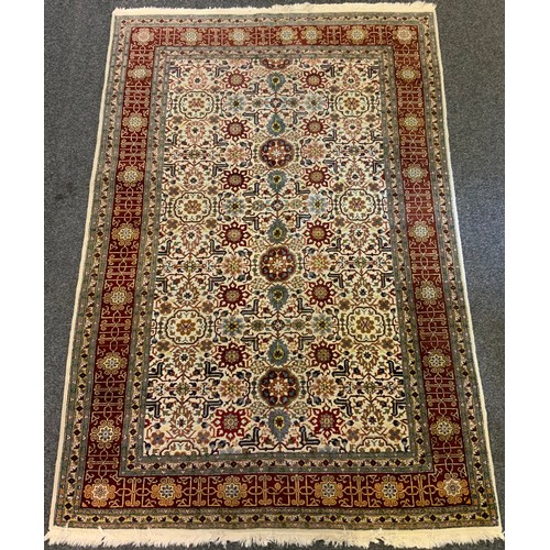 175 - A Caucasian hand-made rug, large central field with stylised floral motifs in shades of red, cream, ... 