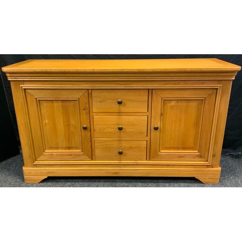 297 - A golden tone light oak sideboard, oversailing top above three central drawers and two cupboard door... 