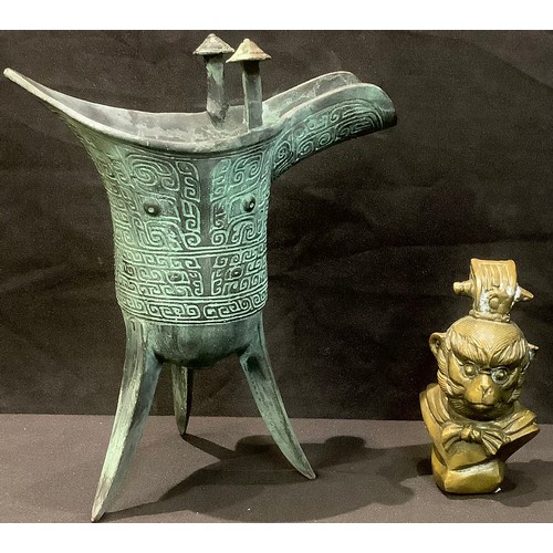 64 - A Chinese verdigris paginated bronze tripod libation cup, cast in the archaic manner; a Chinese monk... 