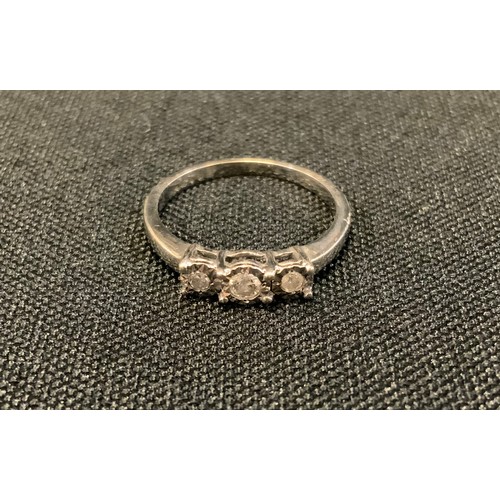 431 - A modern diamond ring, illusion set with three round brilliant cut diamonds, white gold shank, stamp... 