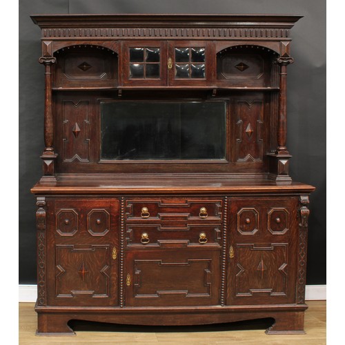 655 - A Jacobean Revival oak sideboard, outswept cornice above a pair of doors and a bevelled rectangular ... 