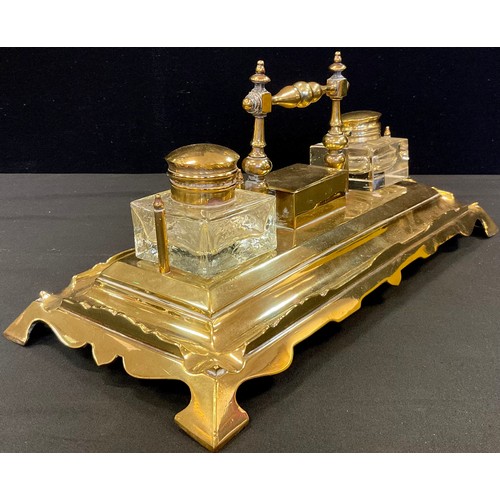 69 - An early 20th century brass standish, central stamp box, flanked by two clear glass wells, the recta... 