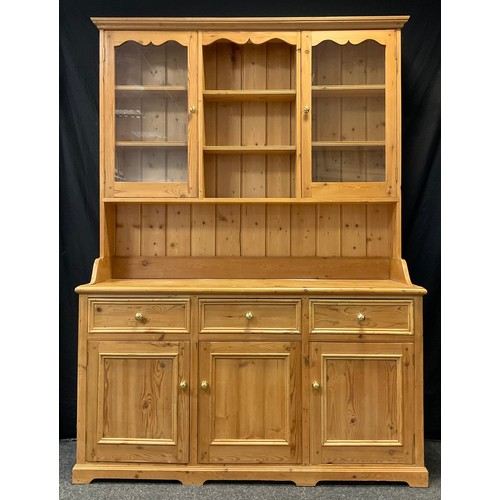 78 - A Pine Kitchen Dresser, the top section having a pair of glazed doors enclosing two tiers of shelvin... 