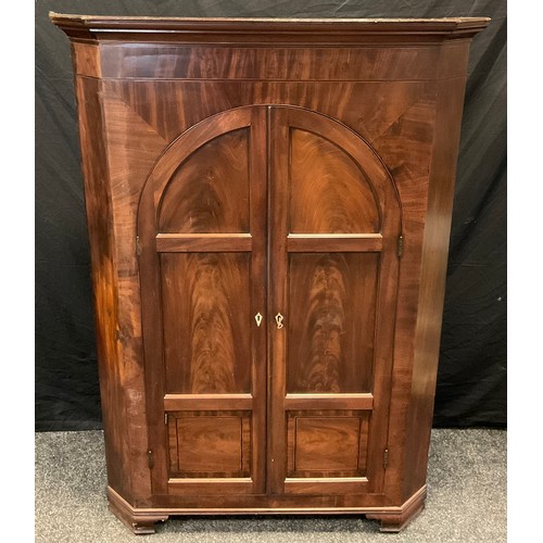 84 - An early Victorian mahogany floor standing corner cupboard, moulded cornice, arched doors, bracket f... 