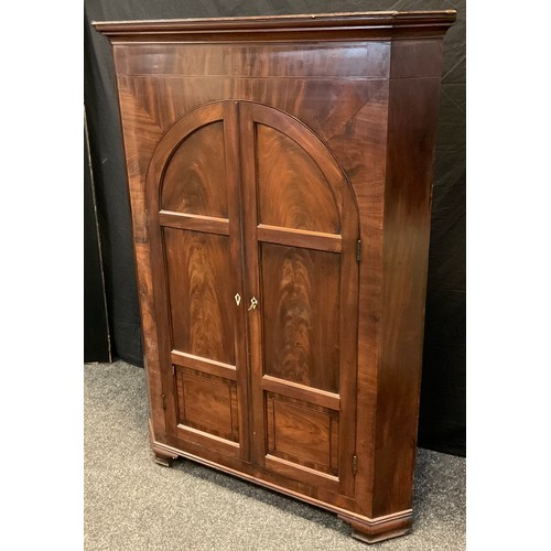 84 - An early Victorian mahogany floor standing corner cupboard, moulded cornice, arched doors, bracket f... 