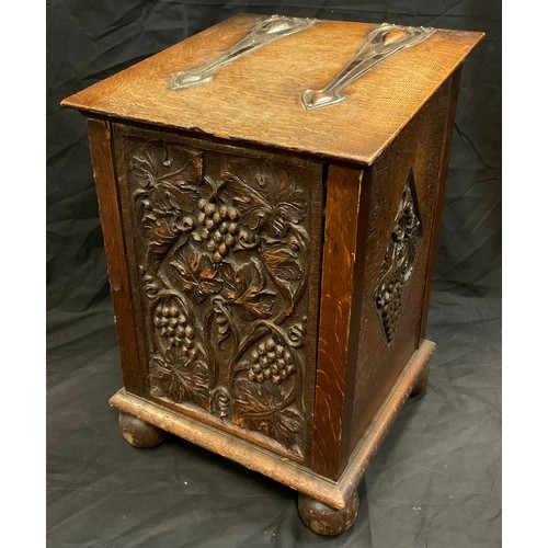 277 - An Arts and Crafts oak slope top coal  bin/purdonium, teh front carved with scrolling vine, copper h... 