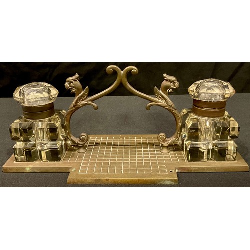 64 - A late 19th century brass desk stand, complete with a pair of cut glass ink wells and hinged covers,... 