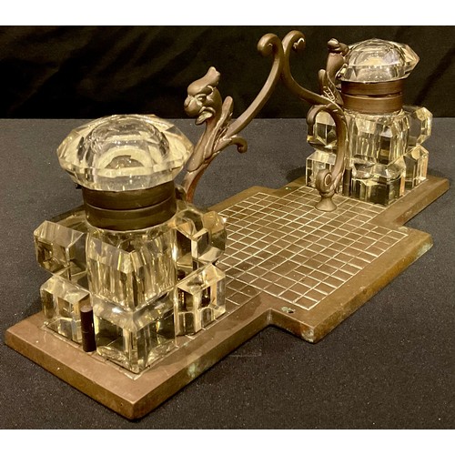 64 - A late 19th century brass desk stand, complete with a pair of cut glass ink wells and hinged covers,... 