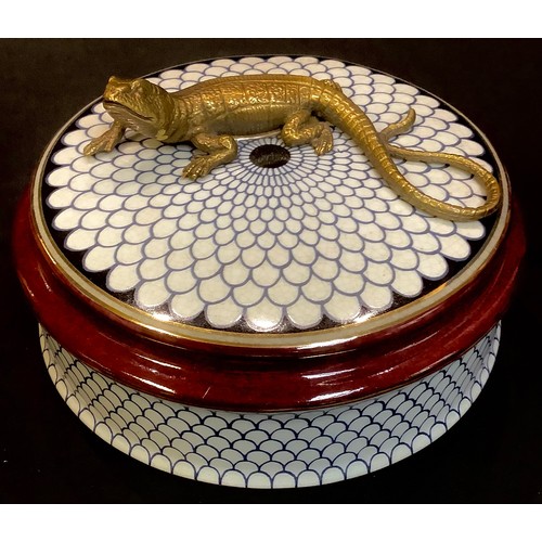 84 - A Continental porcelain circular box and cover, the cover mounted with a bronzed metal lizard, 14cm ... 