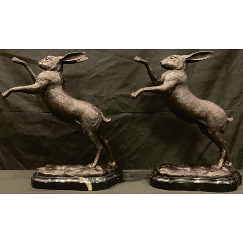 95 - A pair of bronze boxing hares, shaped marble bases, 29cm high, late 20th century