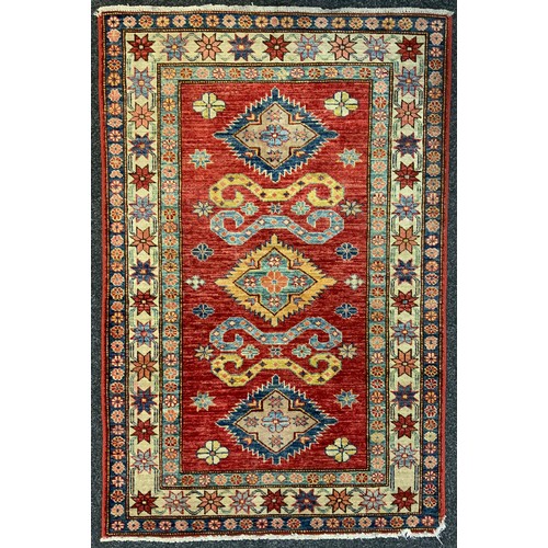 24 - A Middle eastern wool rug, the central field with three diamond medallions, enclosed within a margin... 