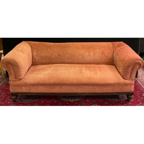 246 - A Victorian mahogany roll arm sofa, carved frieze, turned fore legs, castor terminals, salmon pink u... 