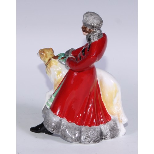 634 - A Royal Crown Derby figure, Olga, she stands, wearing a fur trimmed red trench coat holding a Borzoi... 