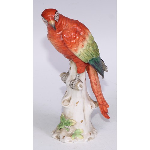 728 - A Continental porcelain model, of a parrot, perched upon an oak tree stump, coloured in tones of gre... 