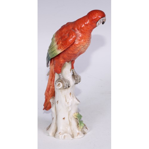 728 - A Continental porcelain model, of a parrot, perched upon an oak tree stump, coloured in tones of gre... 